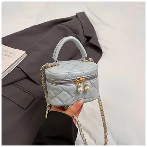 Detail of light blue quilted mini bag featuring pearl zipper and gold chain strap