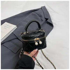 Detail of mini black quilted cylinder bag with gold chain and pearl zipper puller