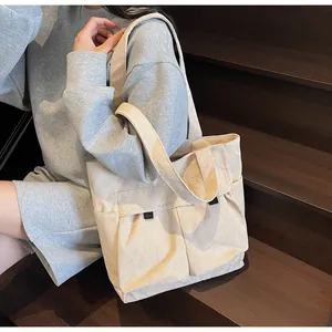 Close-up of beige corduroy tote bag showing ribbed texture and two front pockets