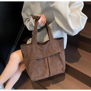 Detail shot of brown corduroy tote bag showing soft ribbed texture and front flap pocket