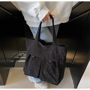 Detail of black corduroy tote bag showing large front pockets and ribbed texture