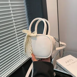 Minimalist white oval crossbody bag with lace bow detail and adjustable shoulder strap