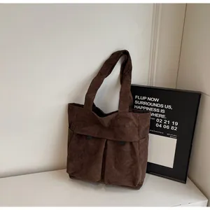 Detail view of the brown corduroy tote bag showing front pockets and ribbed texture