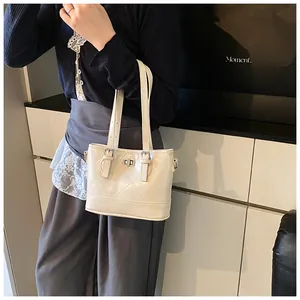 Detail of cream quilted handbag featuring a silver twist-lock and elegant metal hardware