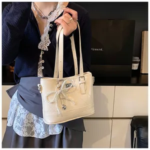 Detail of quilted beige shoulder bag with pearl bow and silver heart pendant detail