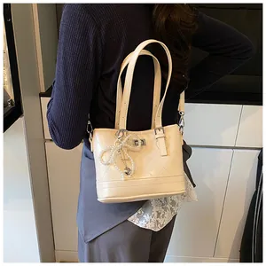 Close-up of cream quilted shoulder bag with pearl bow charm and heart metal pendant