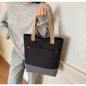 Side view of a minimalist canvas tote bag featuring color-block design and metal rivets