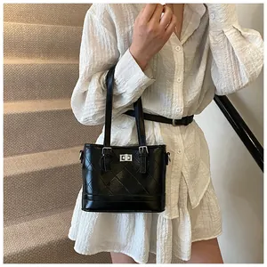 Detail view of the black quilted stitching texture and glossy leather on the handbag