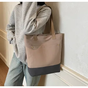Detail view of the two-tone canvas tote bag featuring a front pocket with metal stud