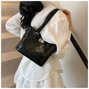 Detail of a black quilted shoulder bag with silver turn-lock clasp shown on a model