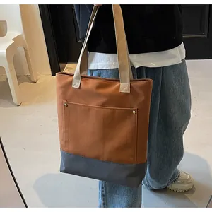 Detail of caramel canvas tote bag showing reinforced metal rivets and large front pocket