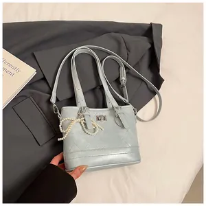 Detail shot of light blue quilted handbag with pearl bow and silver twist lock closure