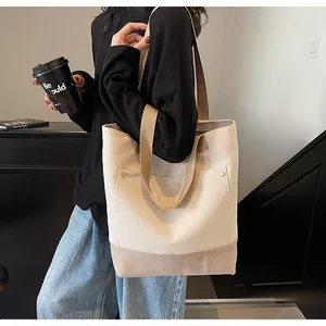 Detail of two-tone canvas tote bag with shoulder straps and exterior pocket with rivets