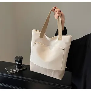Detail of canvas tote bag with contrast khaki trim and metal rivet pocket accent