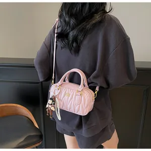 Bolso acolchado rosa con detalles dorados, colgante de perlas y pequeño peluche