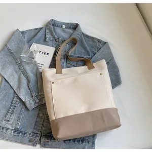 Detail of canvas tote bag showing outer pocket with gold rivets on denim jacket