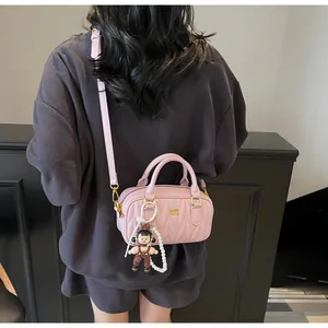 Detalle de bolso rosa acolchado con colgante de perlas y correa ajustable de mujer