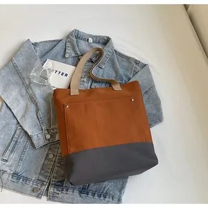 Detailed top view of two-tone canvas tote bag with metal rivet pocket on fabric background