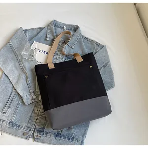 Detail of color-block canvas tote bag with metal rivet accents and front pocket