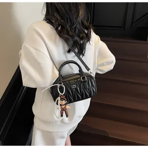 Detalle de bolso acolchado negro con letras blancas y colgante de perlas de moda