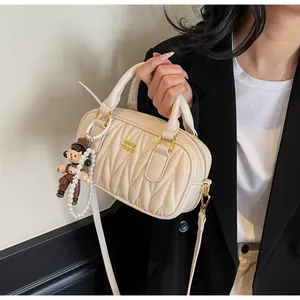 Detalle de bolso acolchado de cuero beige con logo dorado y elegante decoración