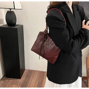 Detail view of burgundy leather tote bag with braided tassel and gold metal hardware
