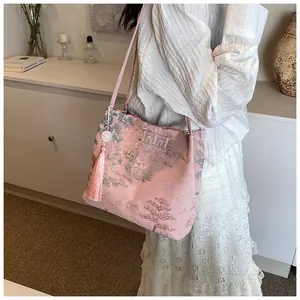 Detailed close-up of pink satin tote bag with traditional Chinese embroidery and tassel