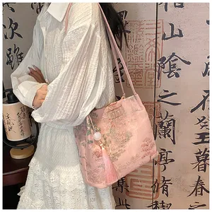 Detailed view of pink silk crossbody bag with traditional Chinese landscape embroidery