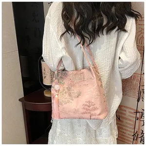 Detail of elegant Chinese style embroidery on pink silk crossbody bucket bag with tassels
