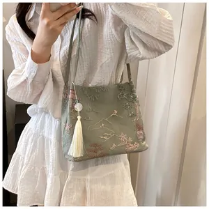 Close-up of traditional Chinese embroidery and tassel on the sage green bucket bag