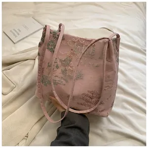 Detailed view of classical Chinese embroidery on a pink satin bucket bag with pavilions