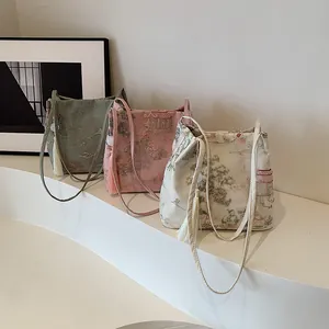 Three Chinese-style embroidered bucket bags in silk fabric with tassels on a white display