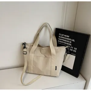 Detail van beige nylon draagtas met waterbestendige stof en reliëflogo