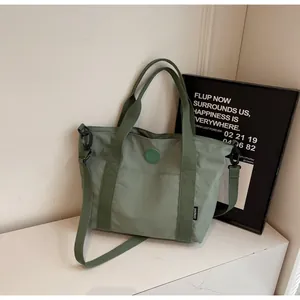 Detail van de erwtengroene nylon draagtas met voorvak en verstelbare schouderriem