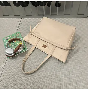 Dettaglio della borsa tote in nylon beige con cordoncini laterali e toppa in pelle marrone