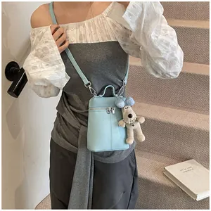 Close-up of light blue litchi grain mini crossbody bag with a cute plush dog pendant