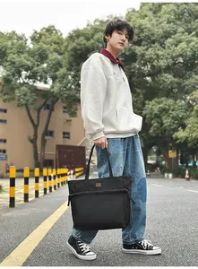 Dettaglio borsa tote in nylon nero con coulisse laterale e patch logo per il pendolarismo