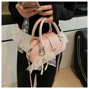 Detail of pink Boston bag featuring a white mesh bow with pearl accents and silver hardware