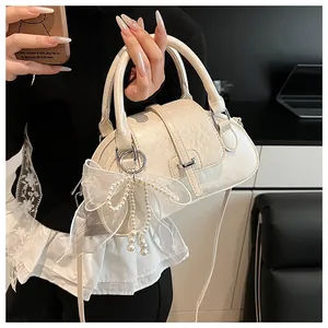 Detail of cream white pillow bag featuring delicate lace bow and pearl tassels accents