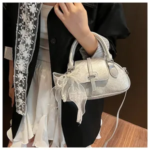 Detail of silver metallic handbag featuring a delicate pearl tulle bow charm accessory
