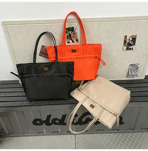 Tre borse tote in nylon nero, arancione e beige con dettagli della tasca con coulisse