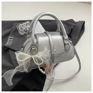 Detailed macro view of silver Boston bag with leather texture and white bow decoration
