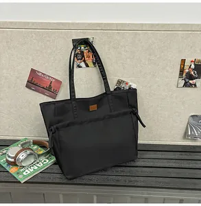 Dettaglio della borsa tote in nylon nero con etichetta in pelle e tasca coulisse