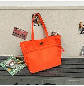 Dettaglio della grande borsa tote in nylon arancione con coulisse e toppa decorativa