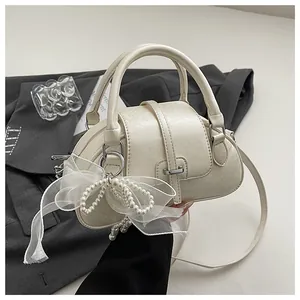 Macro detail of creamy white PU leather Boston bag with pearl mesh bow and silver hardware