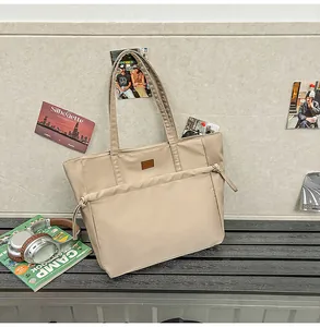 Dettaglio della borsa tote in nylon beige con tasca frontale e nodo a coulisse decorativo