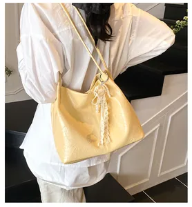 Detail of cream tote bag featuring pleated texture and elegant lace pearl charm