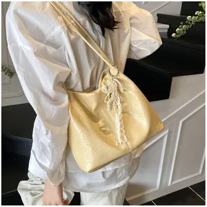 Detail of cream yellow pleated tote bag with delicate lace and pearl pendant decor