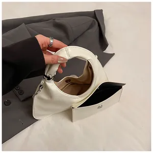 Detail of off-white semi-circular handbag with silver metal ball and inner pouch