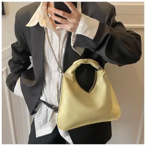 Detail of a yellow triangular handbag with glossy pleated material and silver chain strap